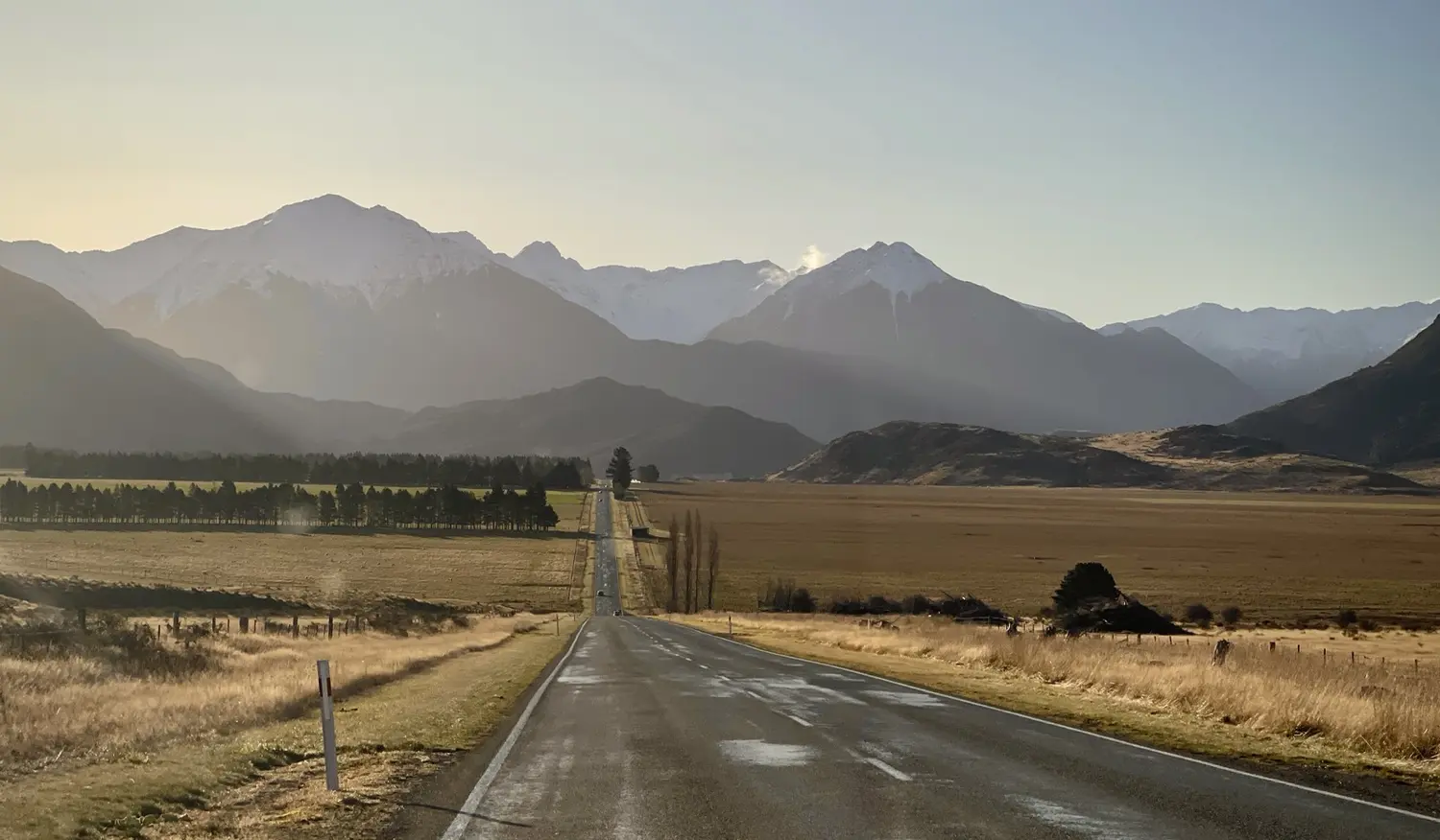 A straight open road running toward distant snow-capped mountains